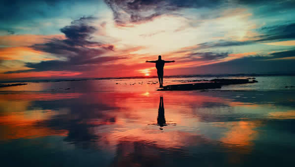 Man worshipping on a beach during sunset