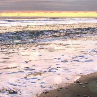 Sunset over a beach with crashing waves