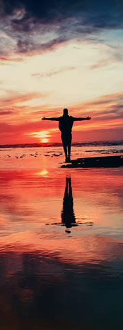 Man worshipping on a beach during sunset